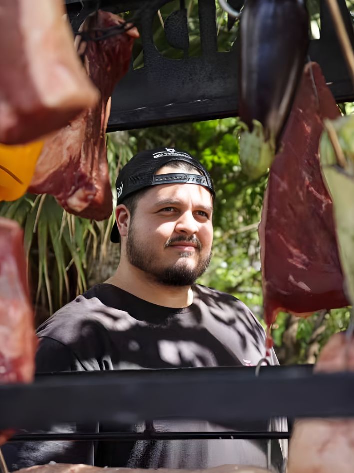 Mestre churrasqueiro Renan Vendrame preparando cortes na brasa